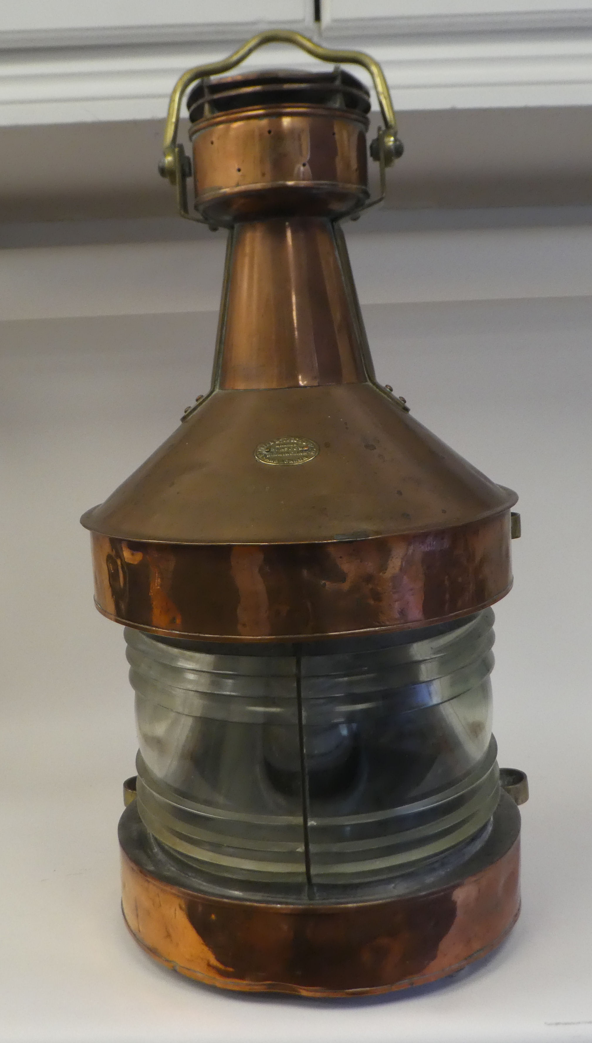 An early 20thC copper and brass cased bulkhead lantern, comprising a covered chimney with a