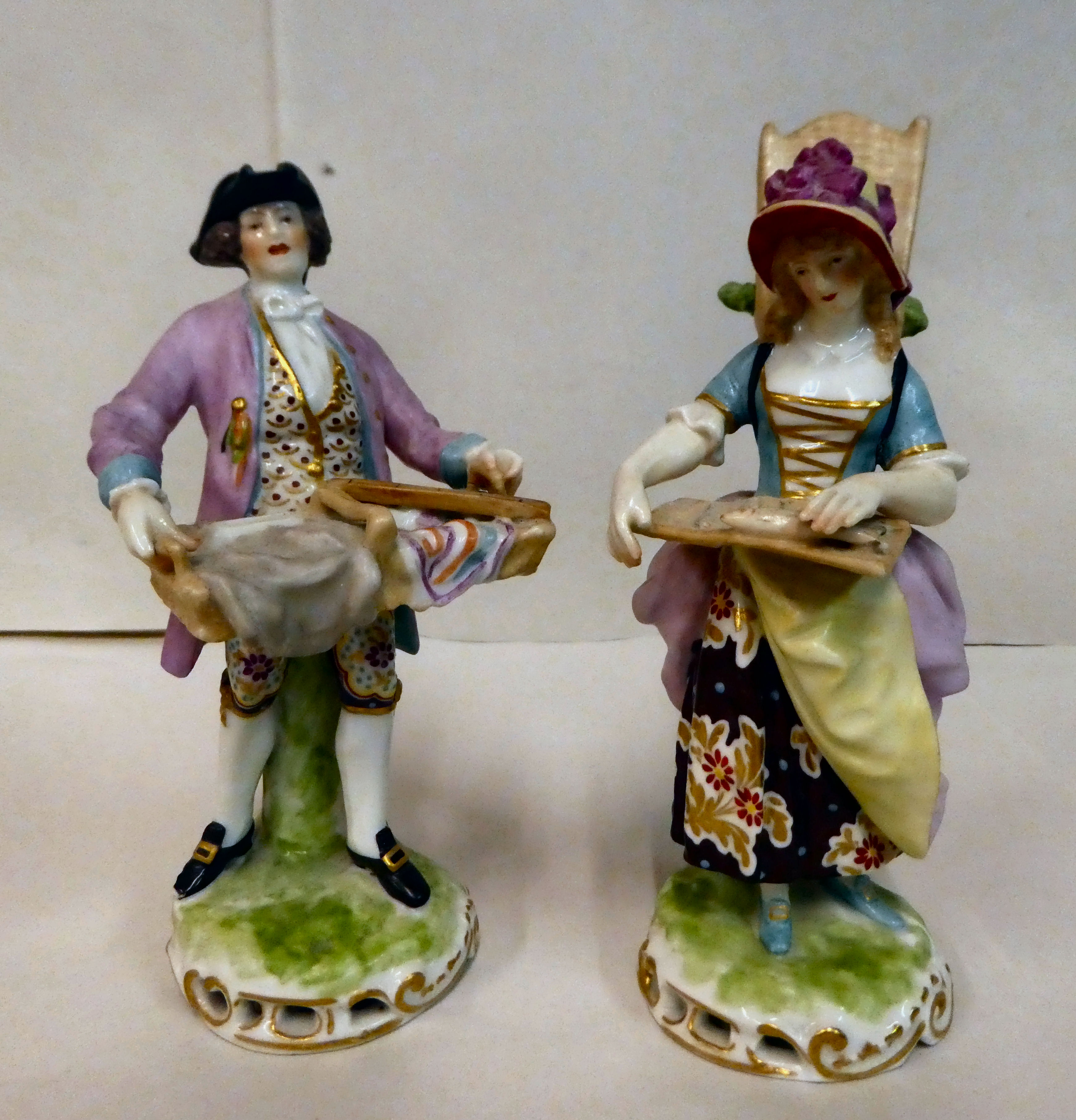 A pair of 20thC Continental porcelain figures, a man and a woman, street vendors  7.5" & 6.5"h