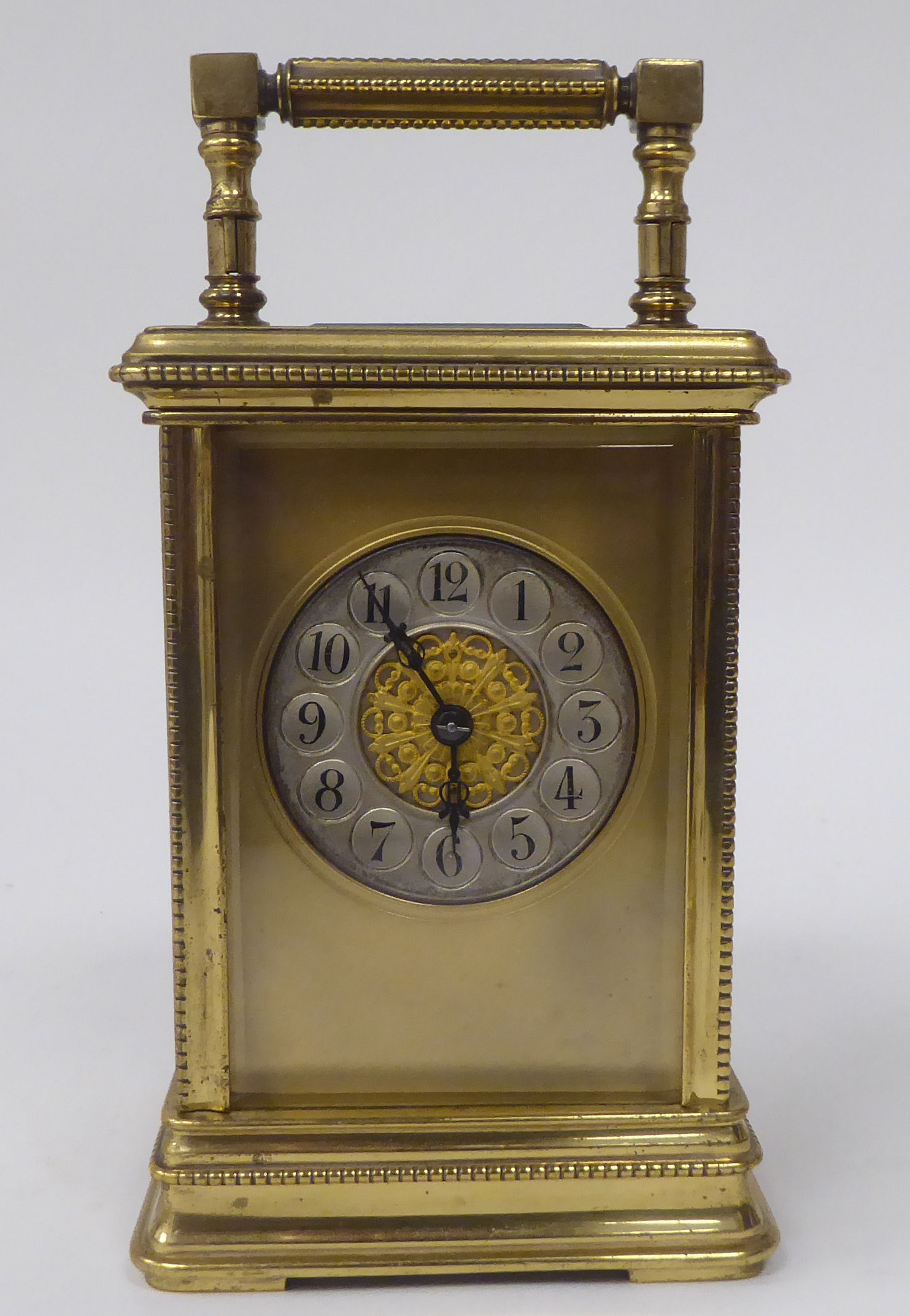 A mid 20thC lacquered brass cased carriage clock with bead bordered ornament, bevelled glass