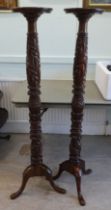 A pair of modern carved mahogany torcheres, raised on tripod bases  57"h