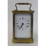 A mid 20thC lacquered brass cased carriage timepiece with bevelled glass panels, a folding top