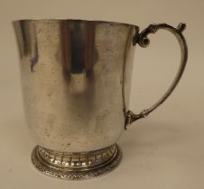 A silver Christening tankard with a flared rim and applied C-scrolled loop handle, on a decoratively