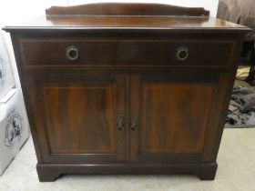 An Edwardian mahogany sideboard with an arched upstand, frieze drawer and two cupboard doors, raised