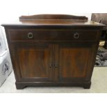 An Edwardian mahogany sideboard with an arched upstand, frieze drawer and two cupboard doors, raised