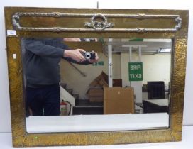 A 1920s mirror, the bevelled plate set in a beaten brass frame  25" x 33"