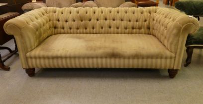 An early 20thC Chesterfield, later part button upholstered in striped fabric, raised on turned