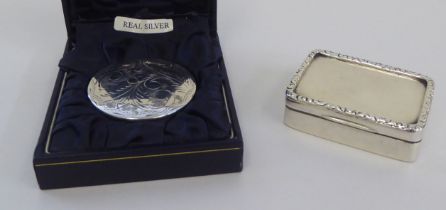 An early 20thC silver rectangular snuff box with a decoratively cast, hinged lid; and a modern