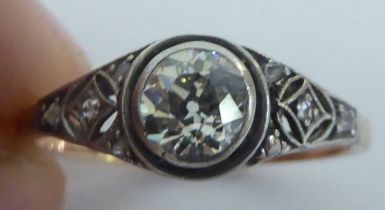 A bi-coloured metal ring, set with a central old cut diamond, flanked by smaller diamonds