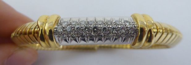 A yellow metal bangle, pave set with diamonds