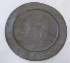 An antique broad rimmed pewter charger, decorated with two figures working in a vineyard  12"dia