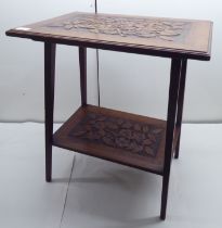 An Edwardian mahogany two tier occasional table carved with flowers and leaves, raised on square,