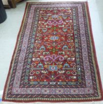 A Persian rug with stylised motifs, on a red ground  86" x 54"