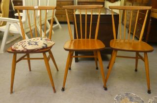 A set of three 1970s Ercol beech and elm framed, spindled back kitchen chairs, raised on turned legs