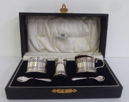 A three piece silver condiments of pierced drum design with blue glass liners  Birmingham 1933