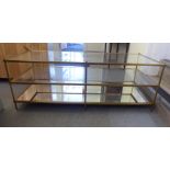 A brass framed and glazed three tier coffee table, the mirrored base raised on tubular legs  17"h