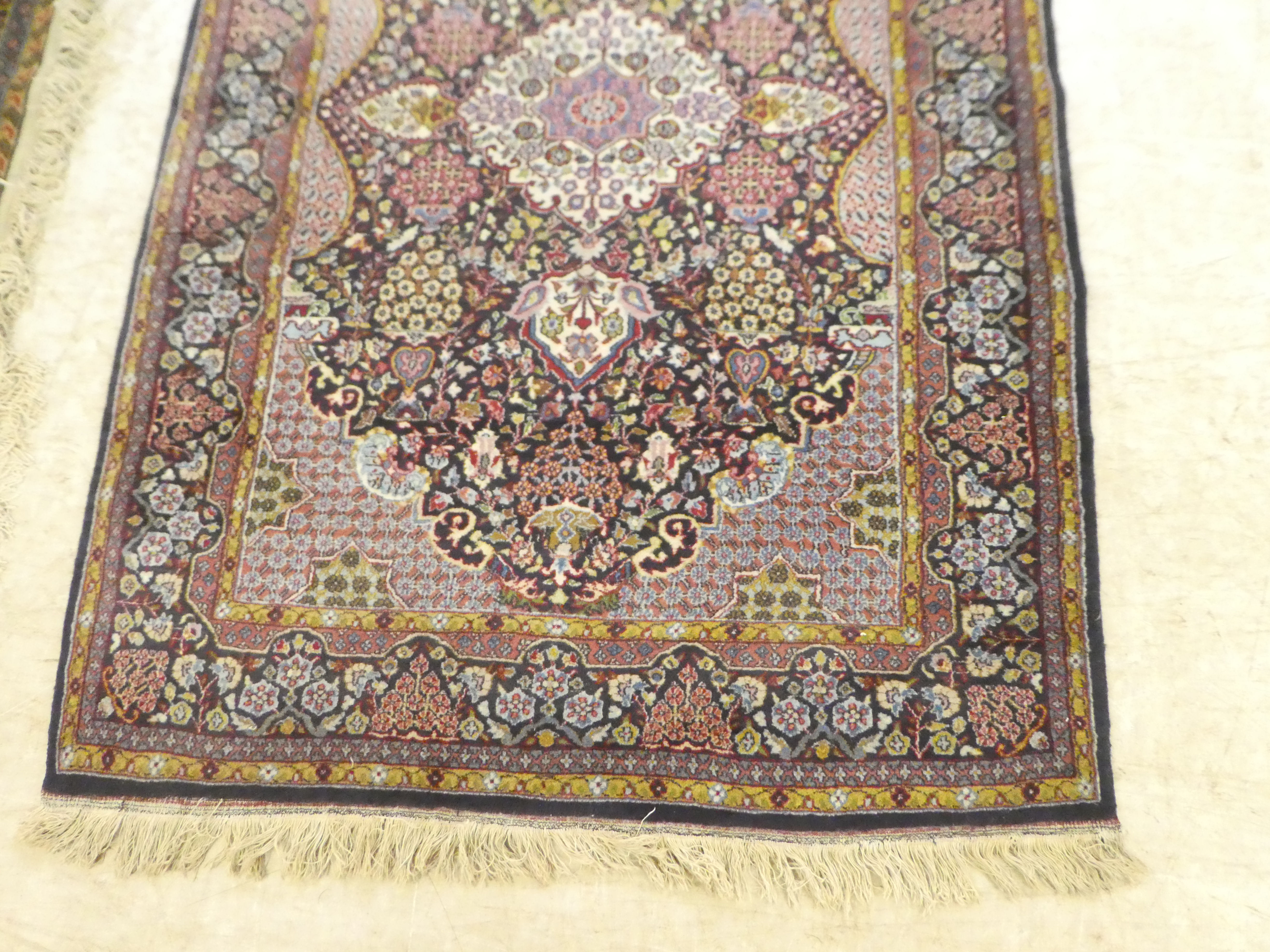 A Persian rug, decorated with a central motif, bordered by stylised designs, on a multi-coloured - Bild 2 aus 4