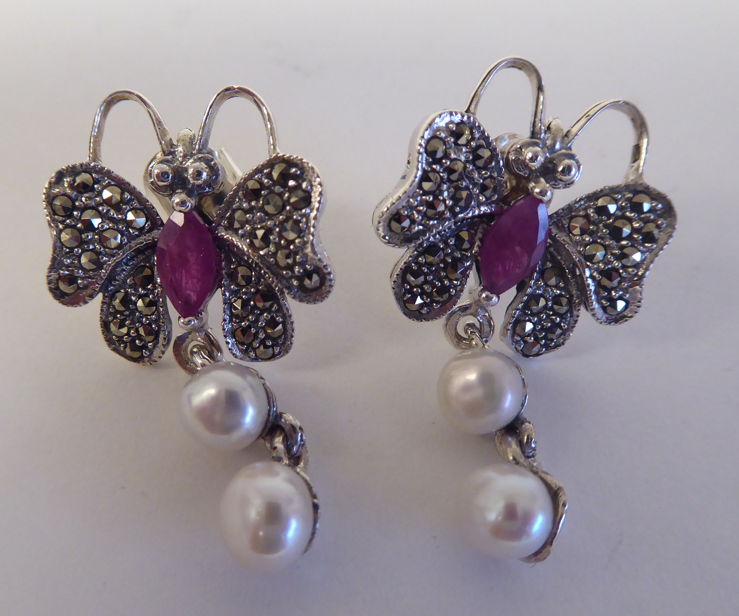 A pair of silver coloured metal and ruby set, butterfly design stud earrings