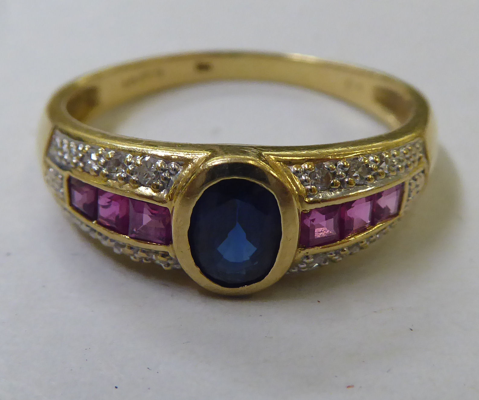 An 18ct gold ring, set with a central sapphire, ruby and diamond shoulders