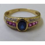 An 18ct gold ring, set with a central sapphire, ruby and diamond shoulders