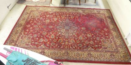 A machine made Oriental rug, profusely decorated with floral designs, on a red ground  79" x 90"