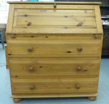 A modern waxed pine bureau with a fall front, fitted interior and three drawers, raised on bun feet