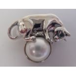 A silver coloured metal brooch, fashioned as a cat, standing on a pearl  stamped Sterling