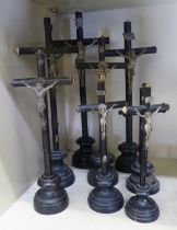 Eight similar ebonised crucifix with variously cast metal Corpus Christi, on turned stands