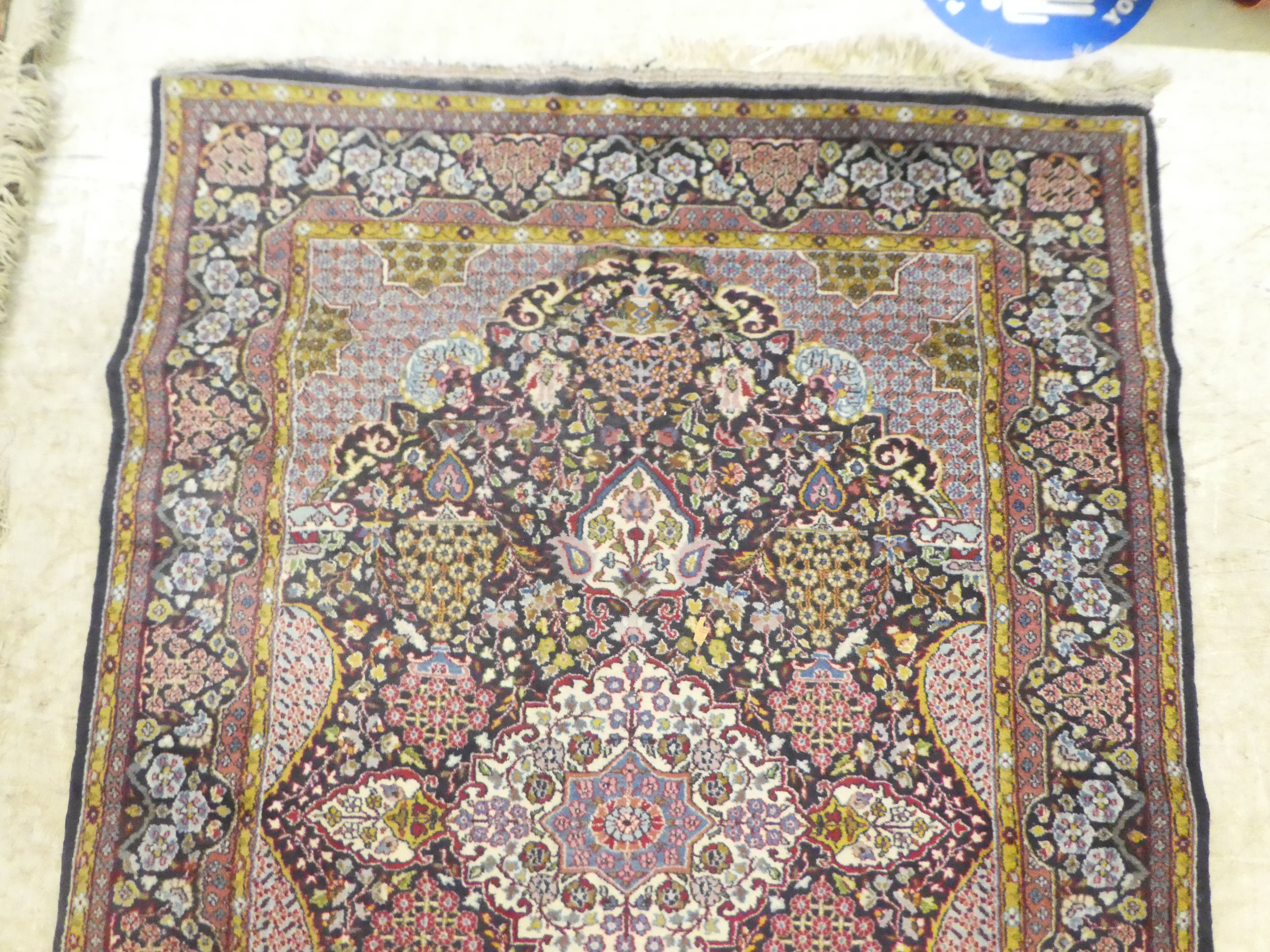 A Persian rug, decorated with a central motif, bordered by stylised designs, on a multi-coloured - Bild 3 aus 4