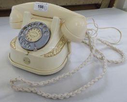 An MFG Company cream coloured plastic telephone with a rotating dial, on a cradle