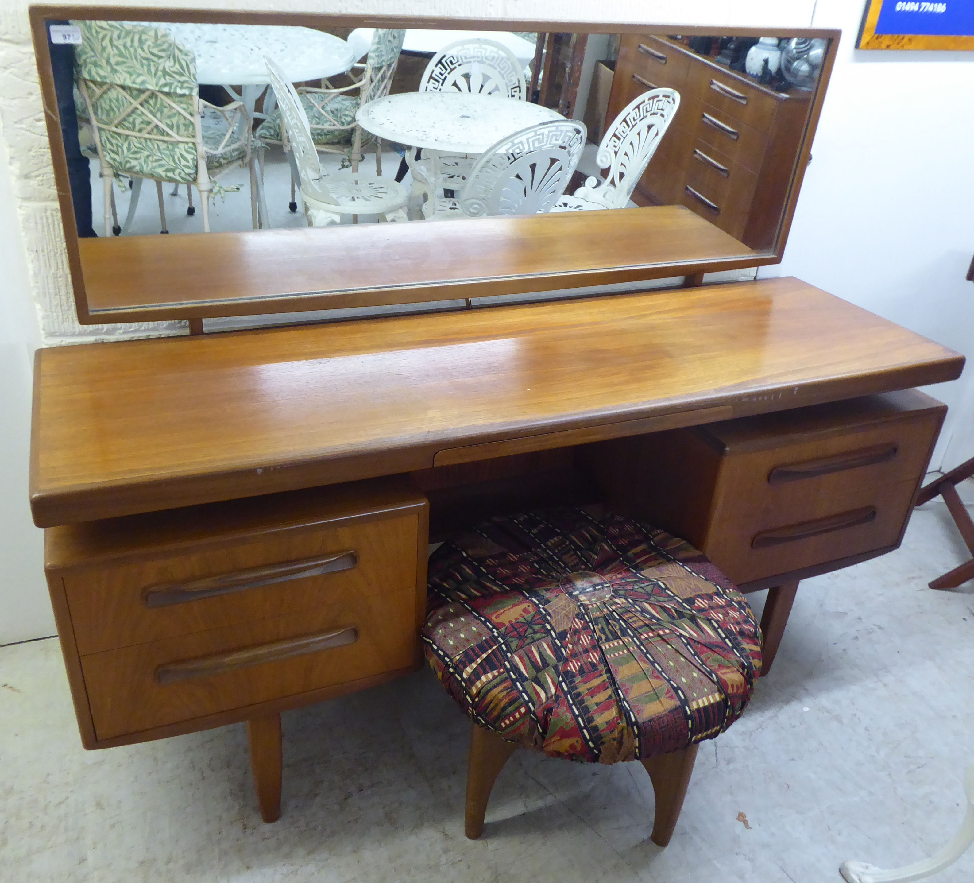 A G-Plan teak kneehole dressing table, surmounted by a horizontal mirror, over an arrangement of