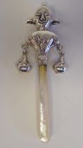 A silver coloured metal baby's rattle, fashioned as a court jester, on a mother-of-pearl teething