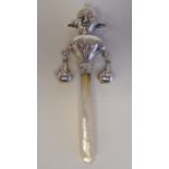 A silver coloured metal baby's rattle, fashioned as a court jester, on a mother-of-pearl teething