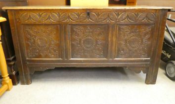 An 18thC oak coffer with a panelled, hinged lid, over a tri-panelled front with carved ornament,