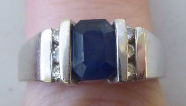 A white metal ring, set with a central sapphire, flanked by six diamonds  stamped 14k