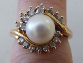A yellow metal starburst ring, set with a central pearl, surrounded by diamonds  stamped 14ct