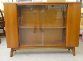 A 1950s walnut finished display cabinet with two sliding glass doors/two cupboard doors, raised on
