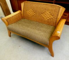 A modern mahogany and cane framed conservatory settee with a cushion seat, raised on splayed legs
