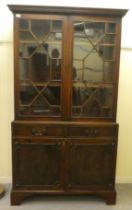 A 20thC reproduction of a Georgian mahogany two part cabinet bookcase with astragal glazed doors,