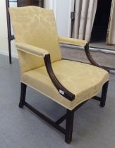 A 20thC ebonised mahogany showwood framed Gainsborough chair with a level back and swept open