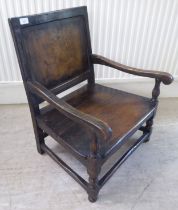 An antique finished, dark stained oak floral marquetry, panelled back, low, open arm chair with a