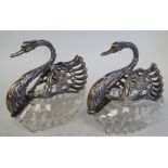 A pair of 20thC cut glass and silver coloured metal mounted swan ornaments with folding wings