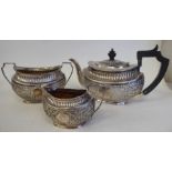 A late Victorian silver three piece tea set of oval form with engraved, chased and demi-reeded