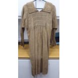 A Continental artisan's brown calico pleated dress with decorative, stone coloured embroidery and