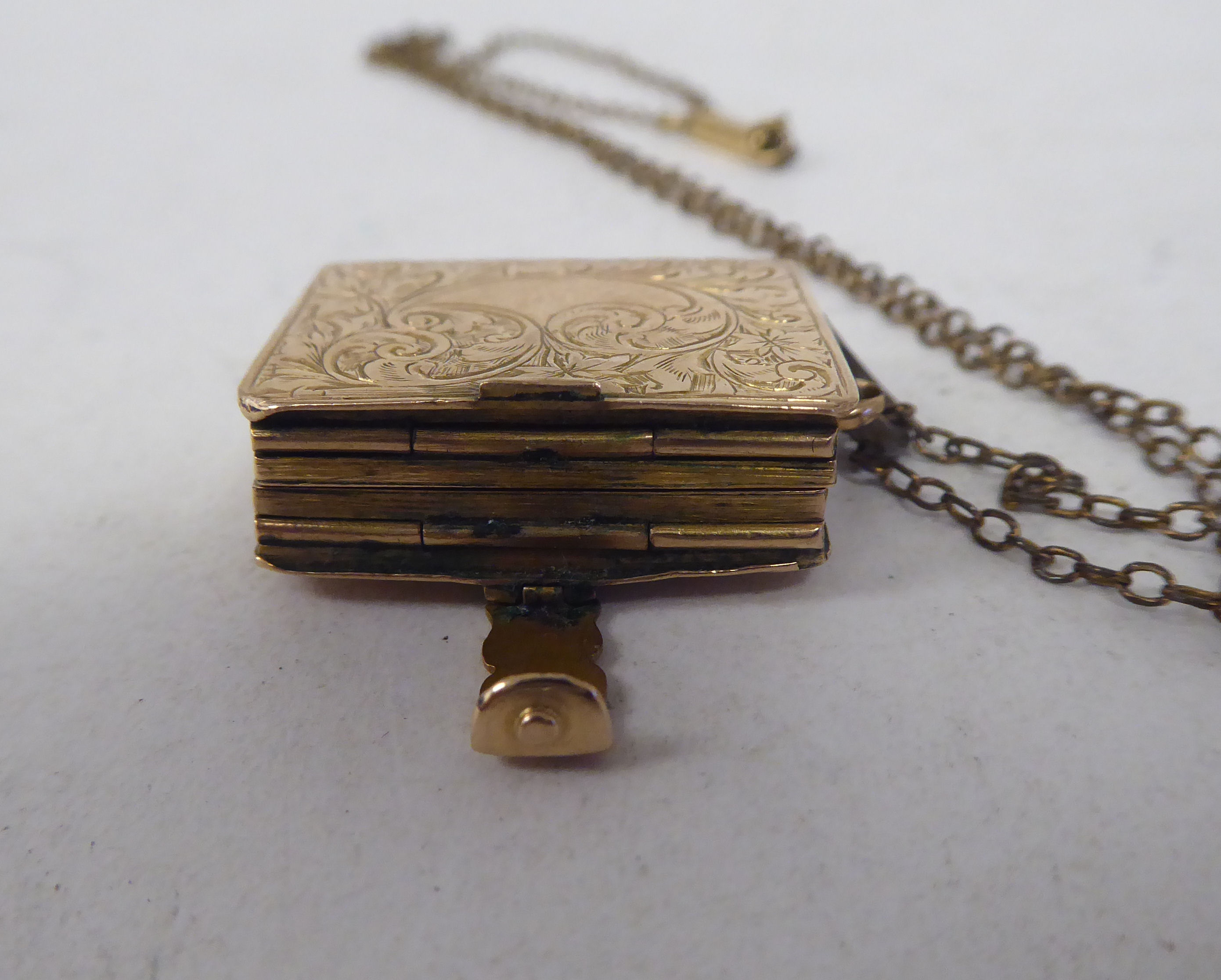 A late Victorian foliate scrolled yellow metal locket, fashioned as a book, on a clasp, revealing - Image 6 of 7