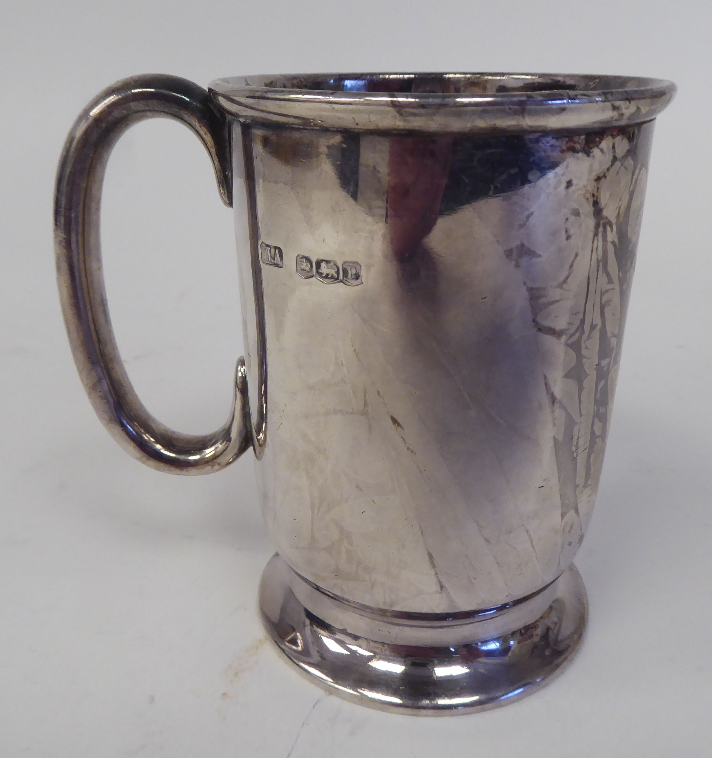 A silver Christening mug with a rolled rim and hollow C-scrolled handle, on a splayed footrim  Henry - Image 2 of 3
