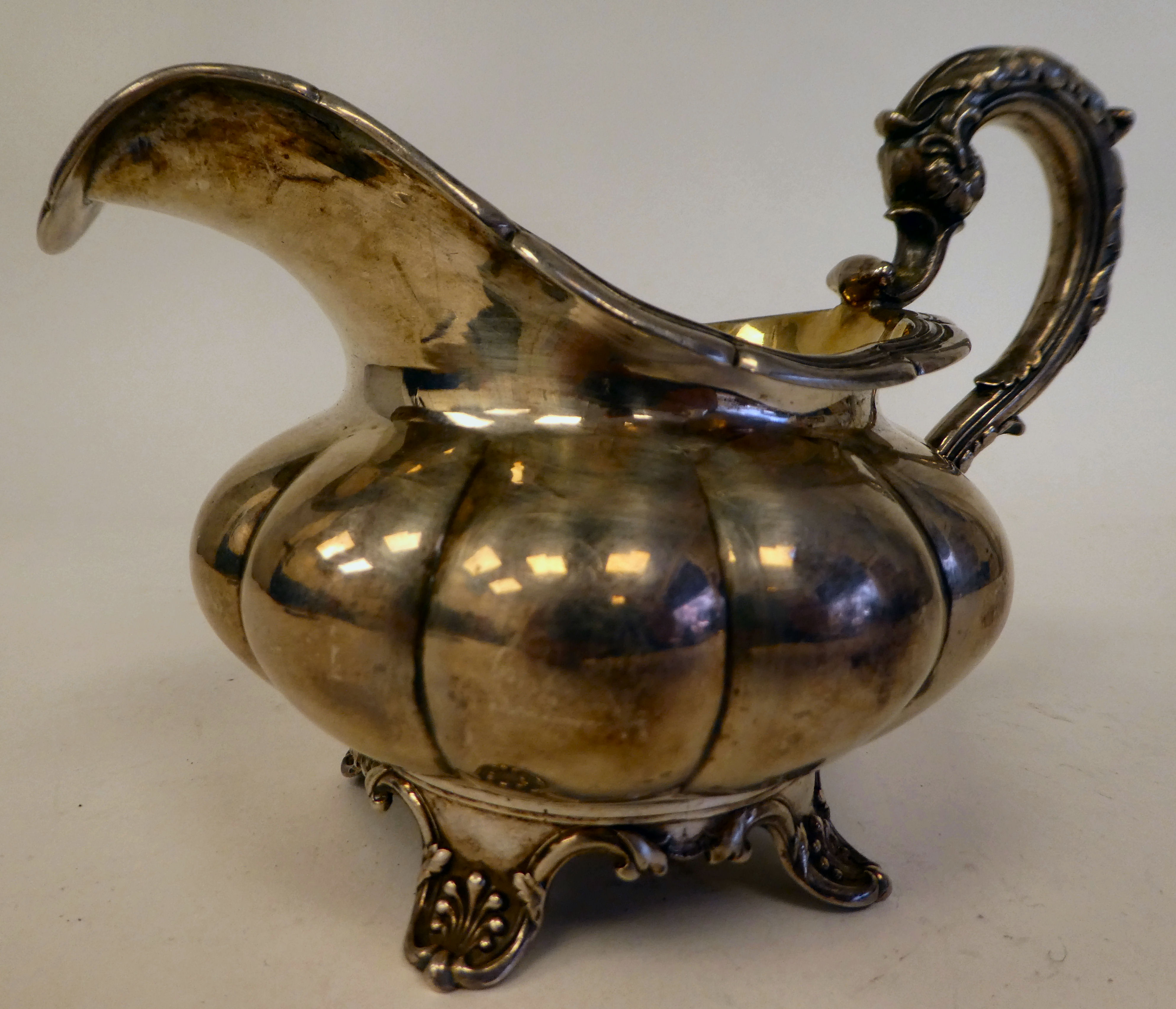 A George IV silver melon shape cream jug with a flared rim on S-scrolled handle, on a shell cast