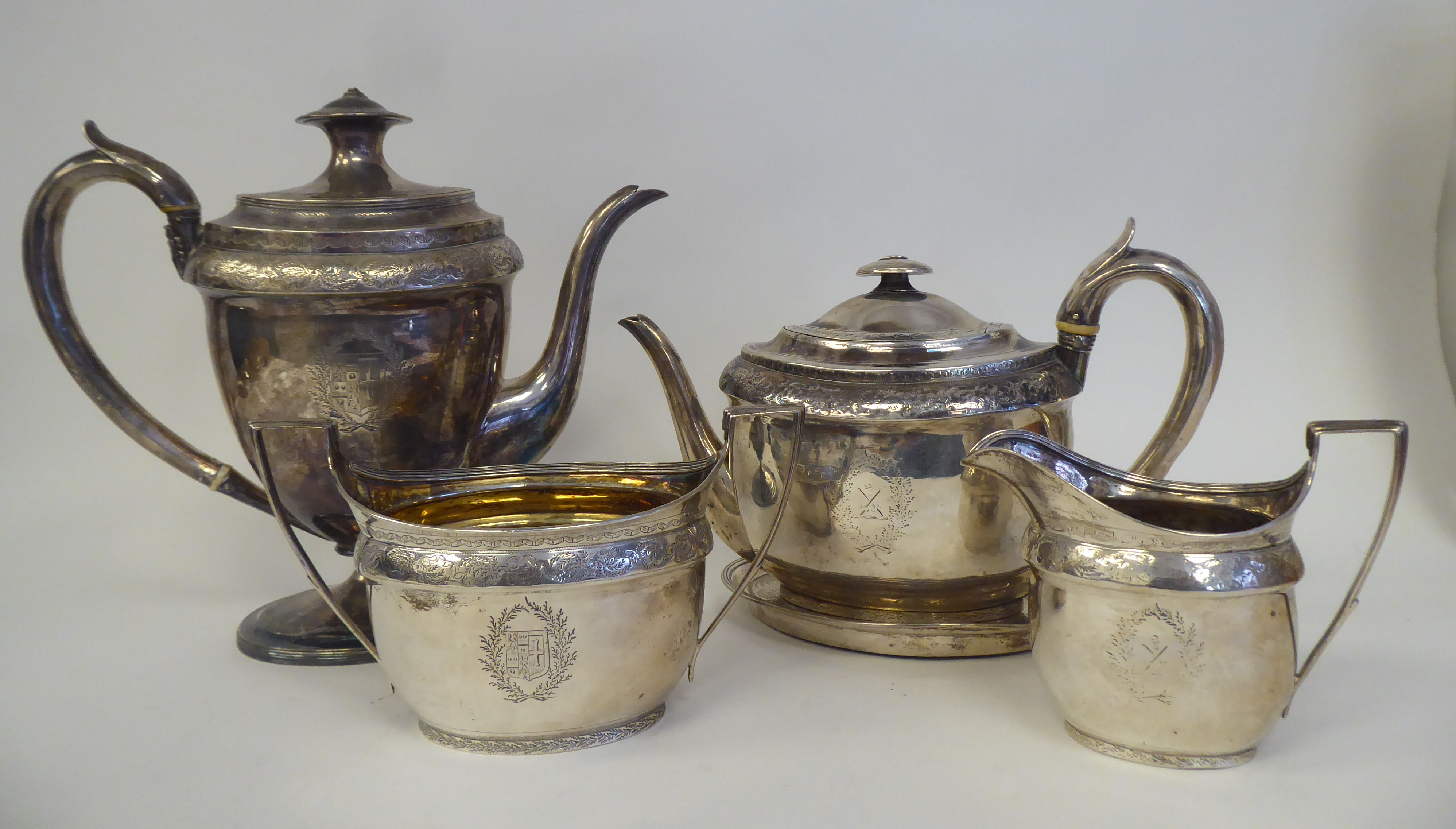 A George III silver five piece tea set of oval form with engraved ornament, including armorials