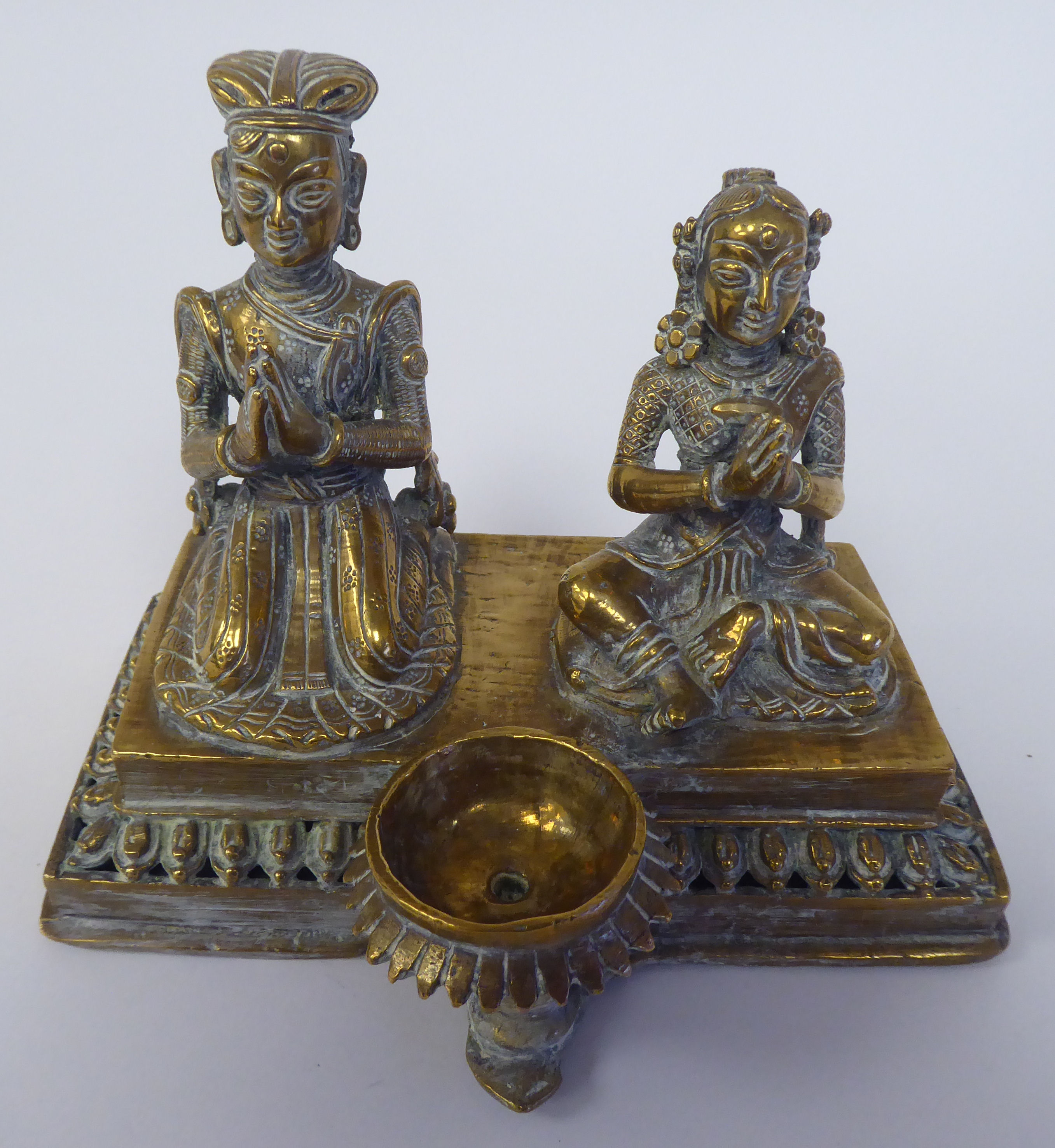 A pair of Asian brass religious deities, seated on a plinth between an outset pedestal vase  5"h