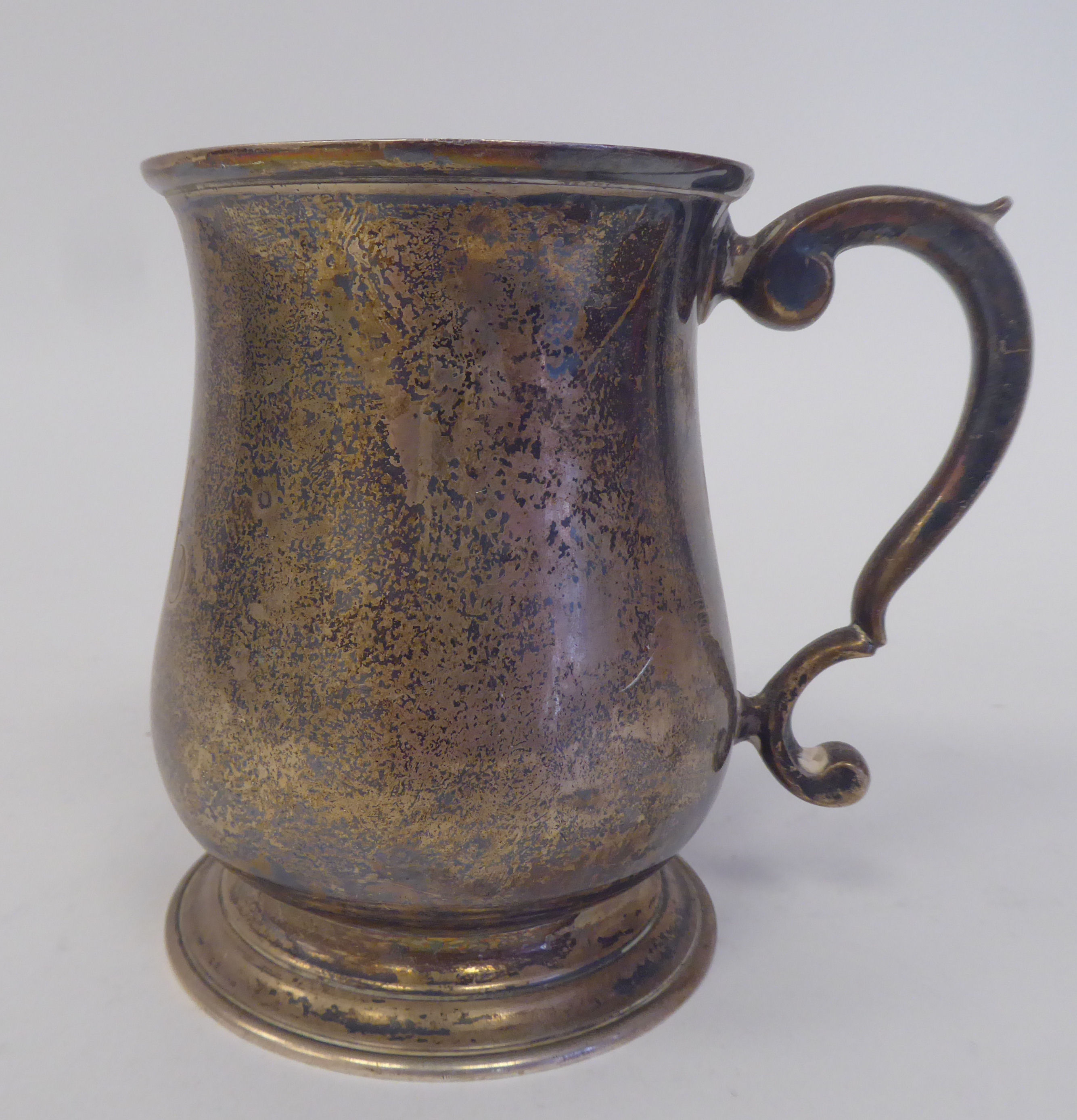 An Edwardian silver Christening mug of baluster form with a hollow, double C-scrolled handle, on a