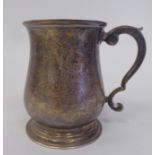 An Edwardian silver Christening mug of baluster form with a hollow, double C-scrolled handle, on a